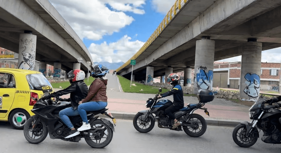 Motorcycles and taxis under a Bogotá overpass